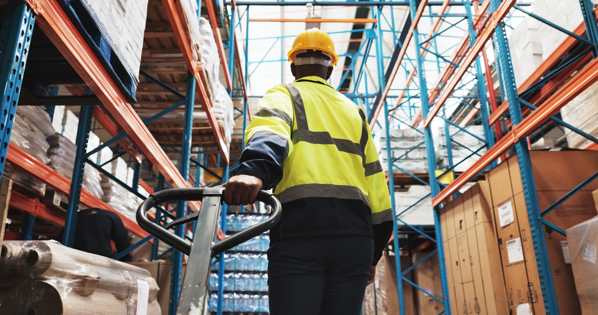 Factory, man and worker pull pallet truck for supply chain, restock inventory or moving freight. Warehouse, engineer and trolley for cargo storage, distribution logistics or back in shipping industry