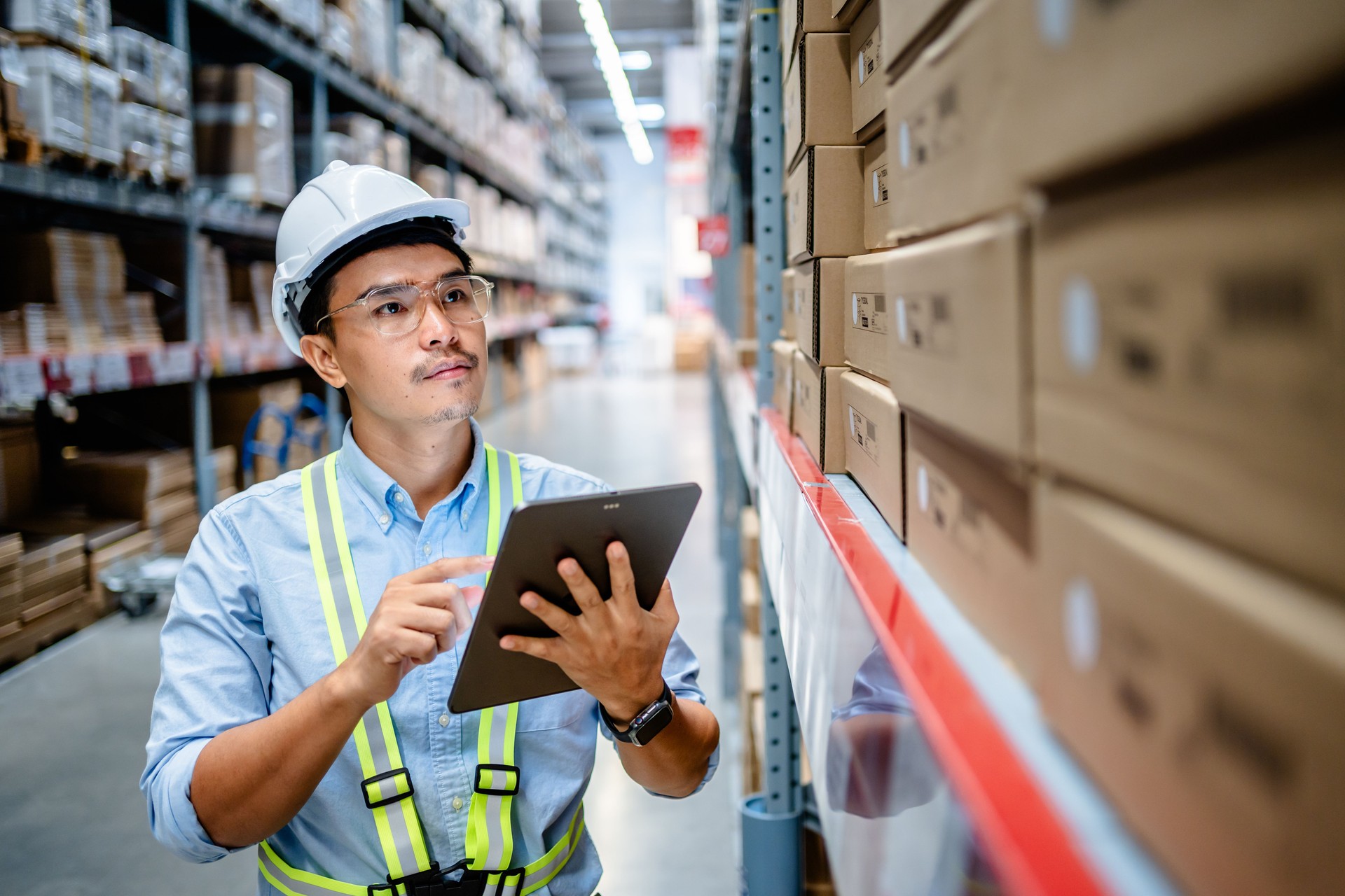 Businessmen or manager use a digital tablet to check the stock inventory on shelves in large warehouses, a Smart warehouse management system, supply chain and logistic network technology concept.